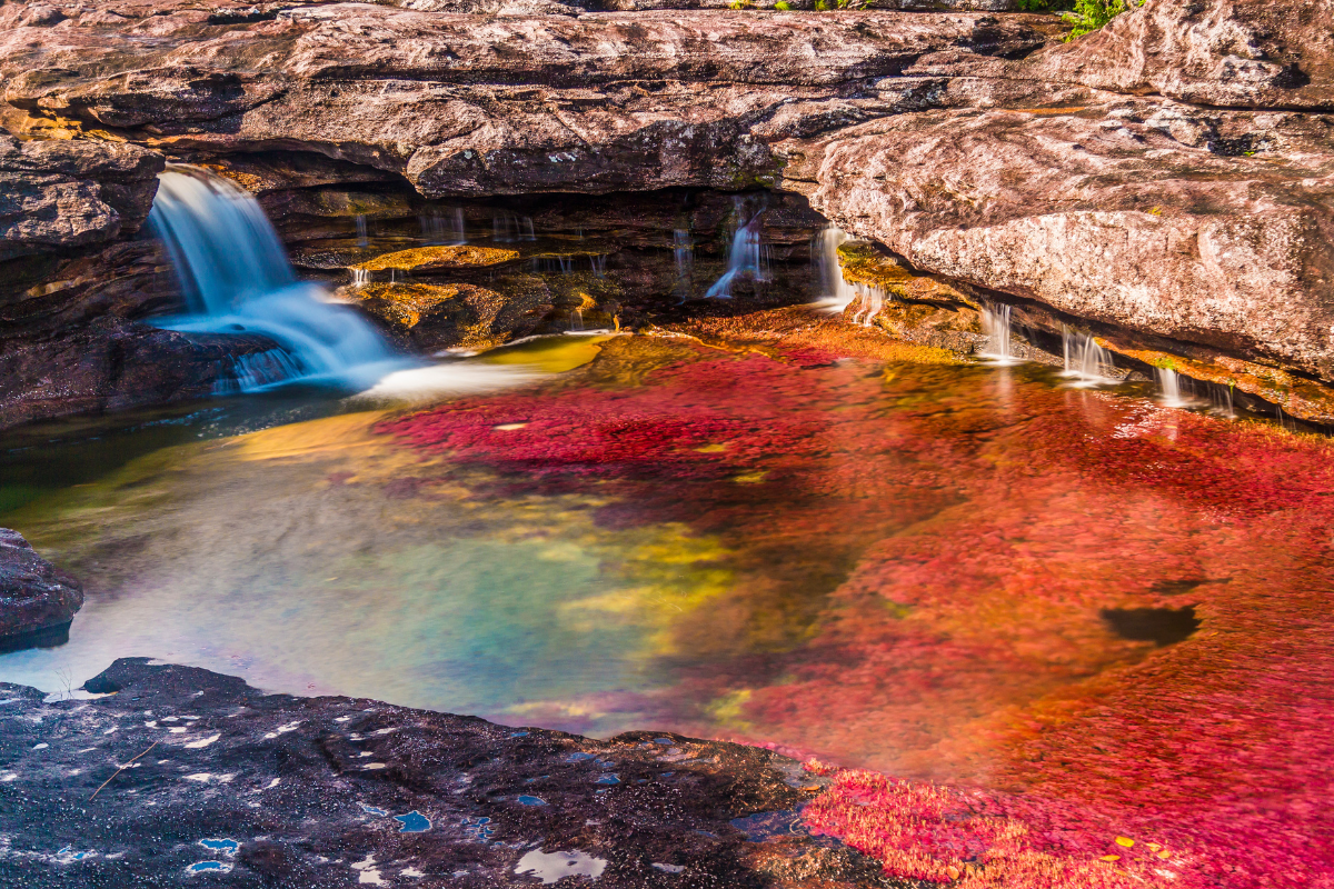 Rock pool with small waterfalls and red, yellow and green colors in Caño Cristales